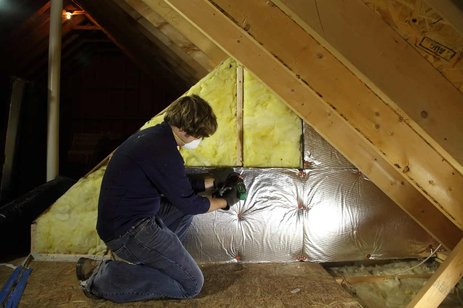 Worker installing insulation in an attic